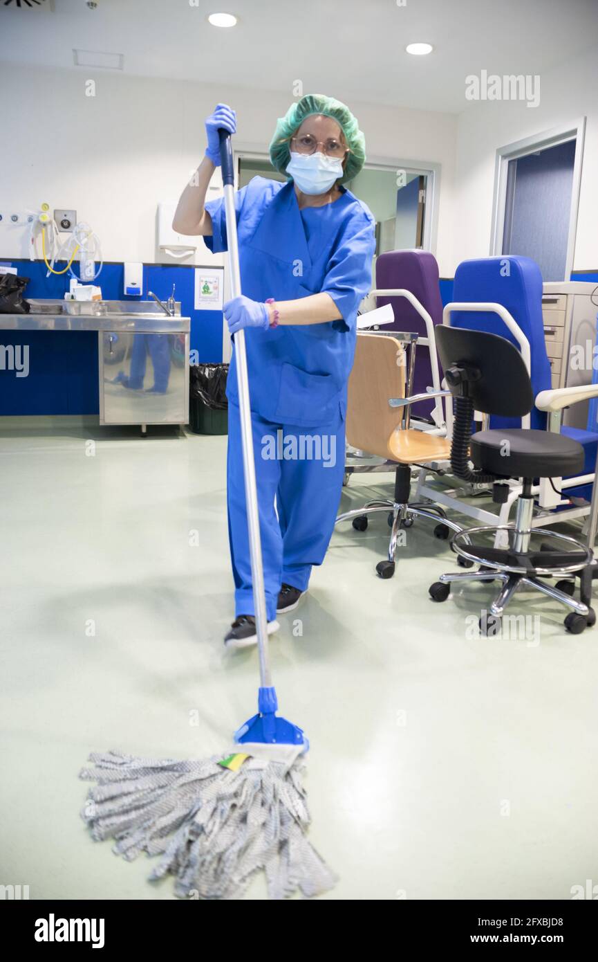 Frau vom Reinigungsservice eines Krankenhauses, die den Boden des Operationssaal mit einem Mopp reinigt. Sanitärkonzept Stockfoto