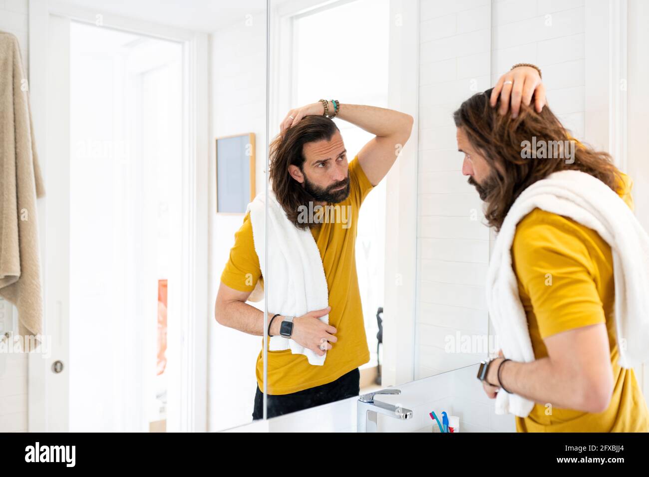Mann mit Kopf in der Hand und Blick auf den Spiegel Stockfoto