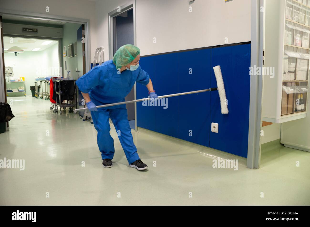 Frau vom Reinigungsservice eines Krankenhauses, die die Wände des Voroperationssaal mit einer speziellen Bürste reinigt. Sanitärkonzept Stockfoto
