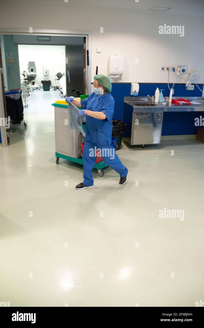 Frau aus dem Reinigungsservice eines Krankenhauses zu Fuß, während die Verbreitung des Tuchs in den vorherigen Operationssaal zu reinigen. Sanitär-Konzept Stockfoto