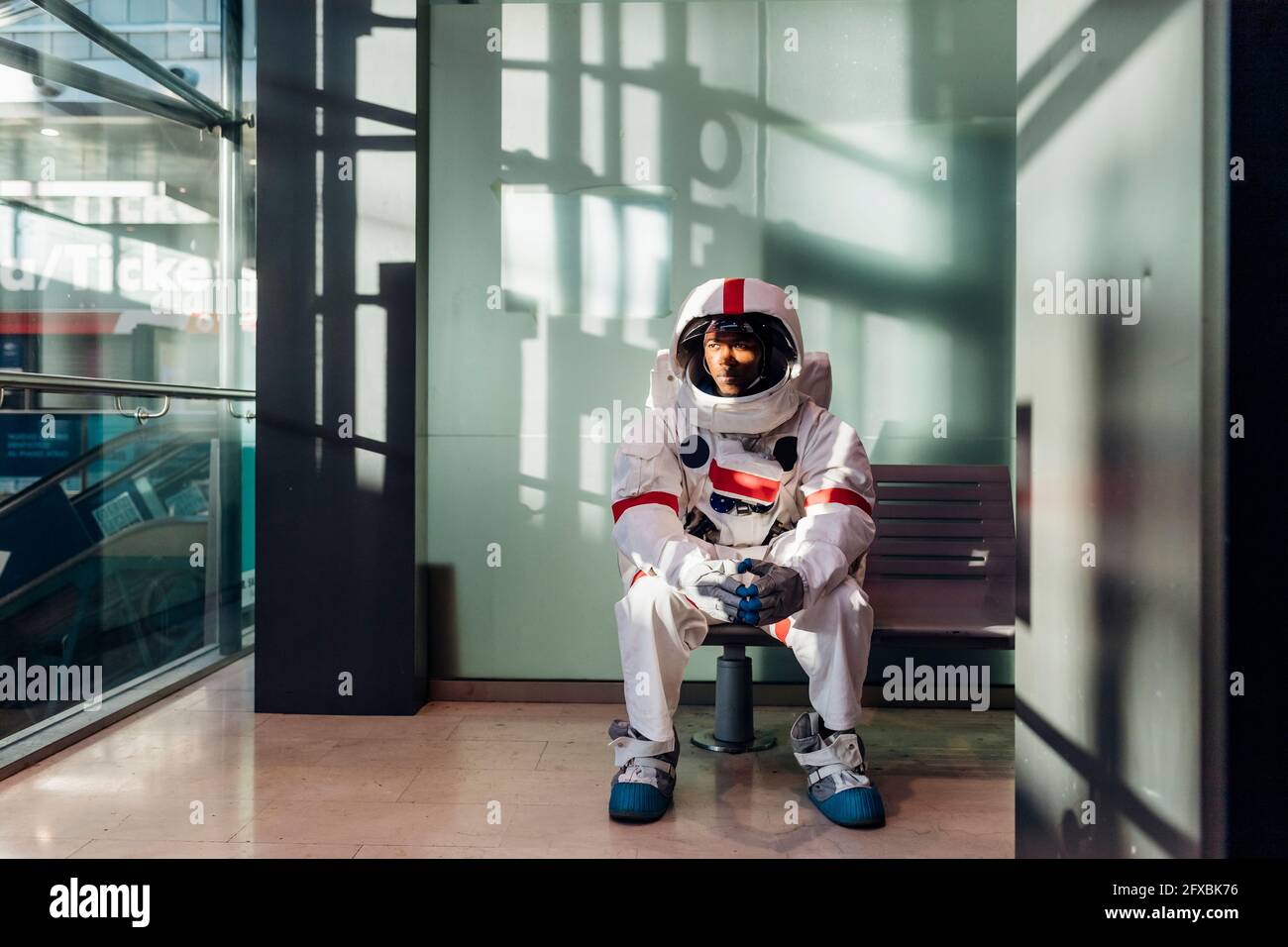Männlicher Astronaut wartet auf der Bank im Korridor Stockfoto
