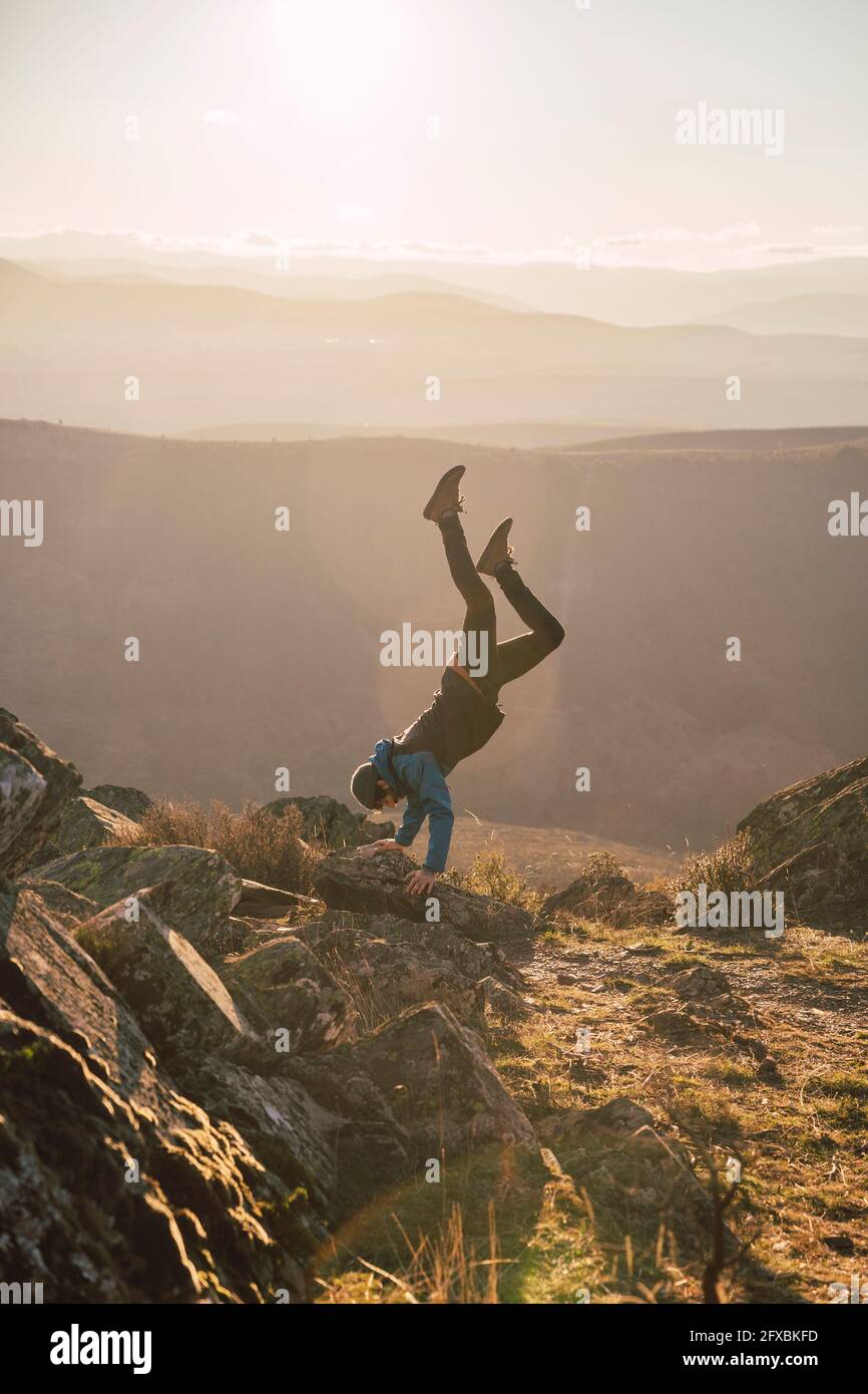 Männliche Sportsperson beim Training beim Handstand am Berg Stockfoto