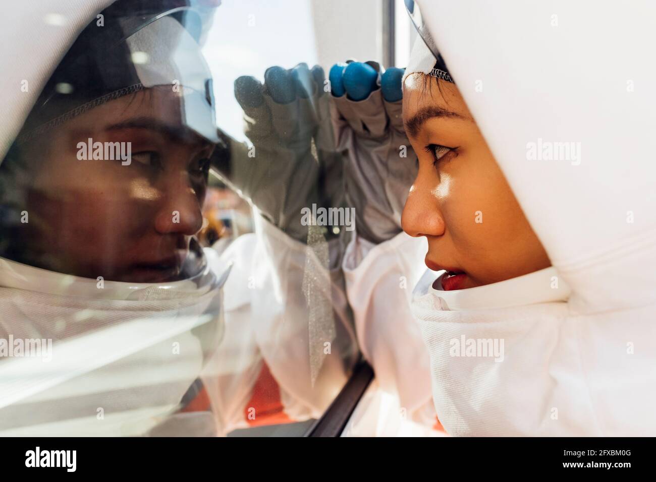 Weibliche Astronautin guckt durch das Glasfenster Stockfoto