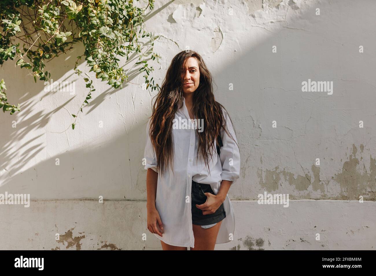 Frau mit der Hand in der Tasche, die vor der Wand steht Stockfoto