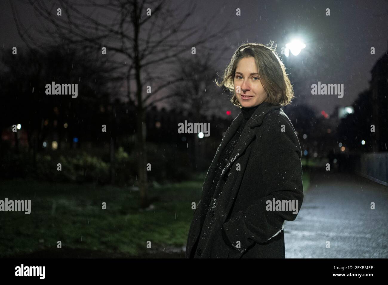 Lächelnde Frau mit kurzen Haaren auf der Straße in der Nacht Stockfoto