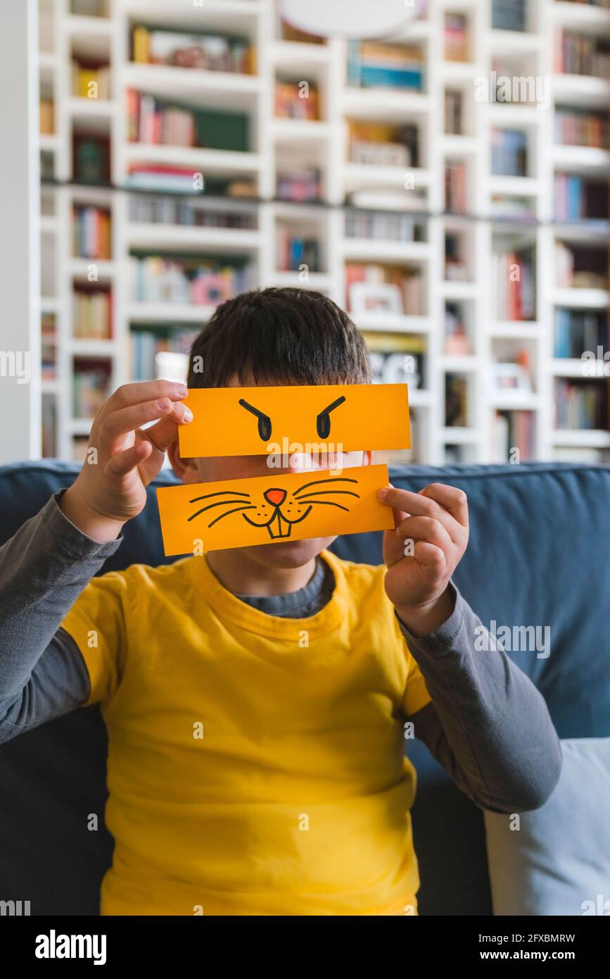 Junge, der zu Hause mit Emoticons auf gelbem Papier spielt Stockfoto