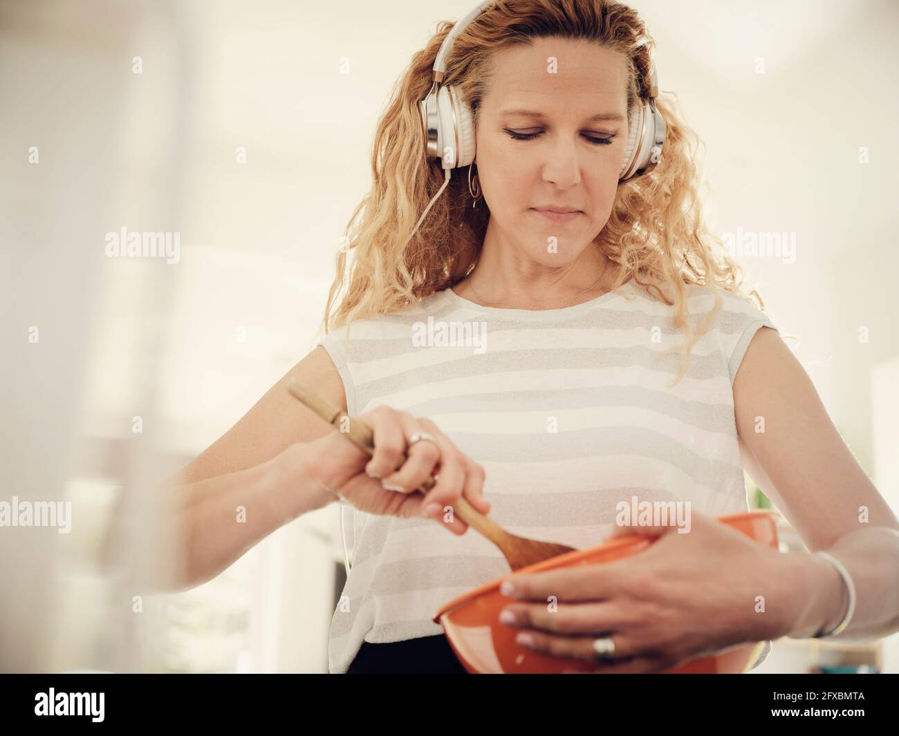 Frau bereitet Essen zu, während sie zu Hause Musik hört Stockfoto