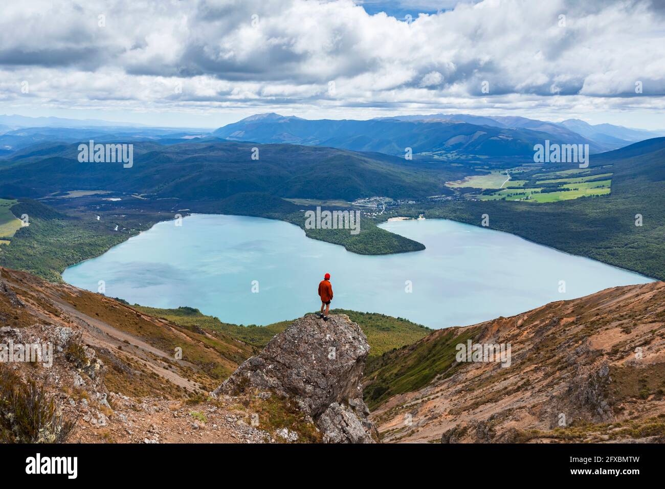 Neuseeland, Tasman District, männlicher Wanderer, der auf einer Felsformation mit Blick auf den malerischen Lake Rotoiti steht Stockfoto