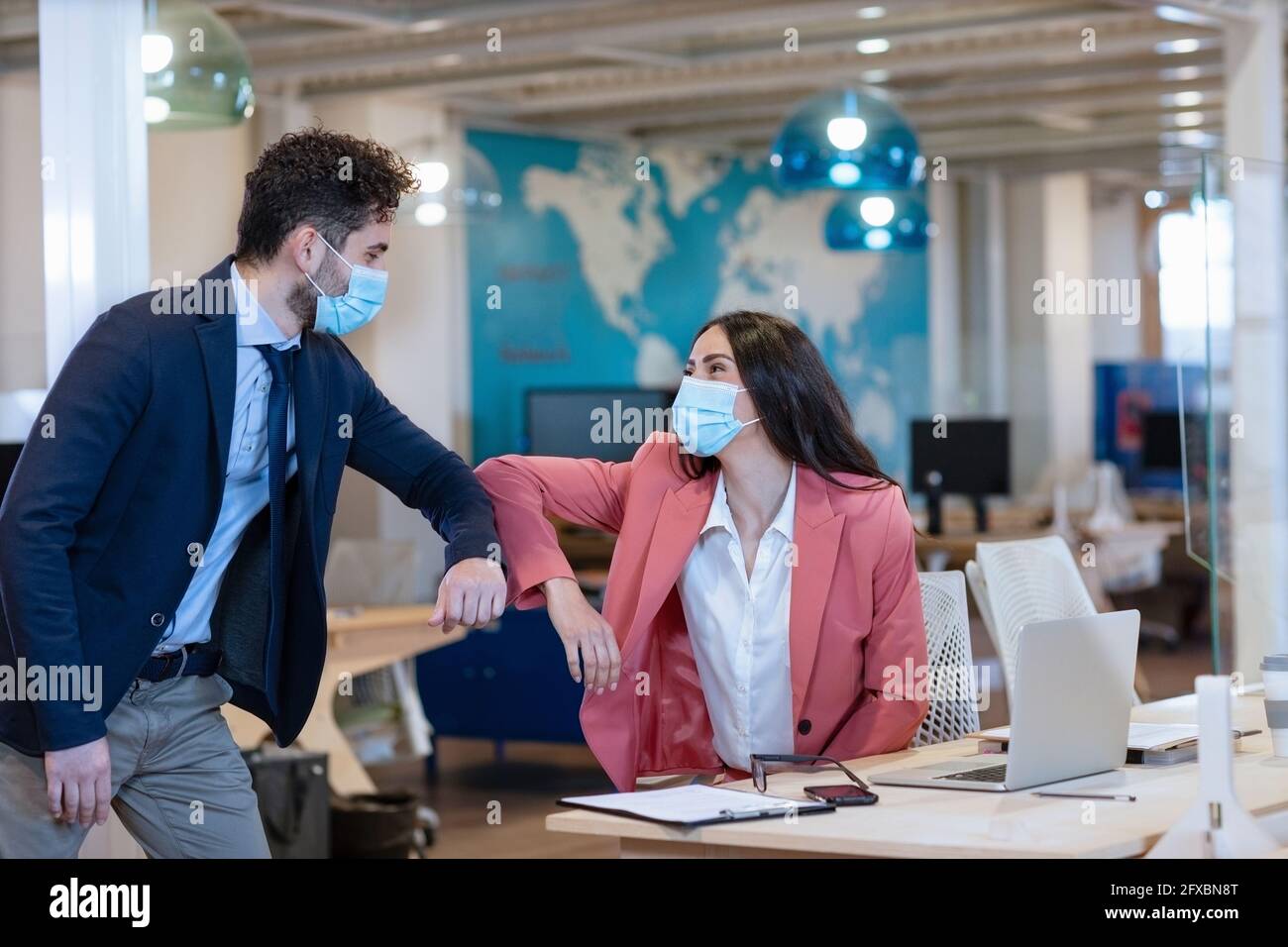 Männliche und weibliche Unternehmer tun Ellenbogenstoß während Pandemie im Büro Stockfoto