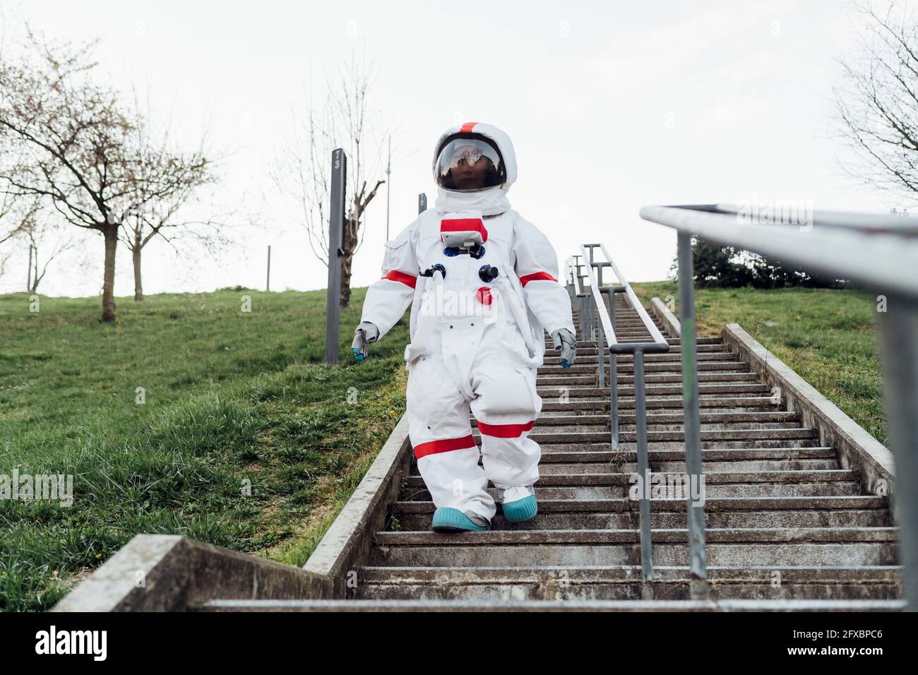 Weibliche Astronautin, die sich auf Stufen im Park nach unten bewegt Stockfoto