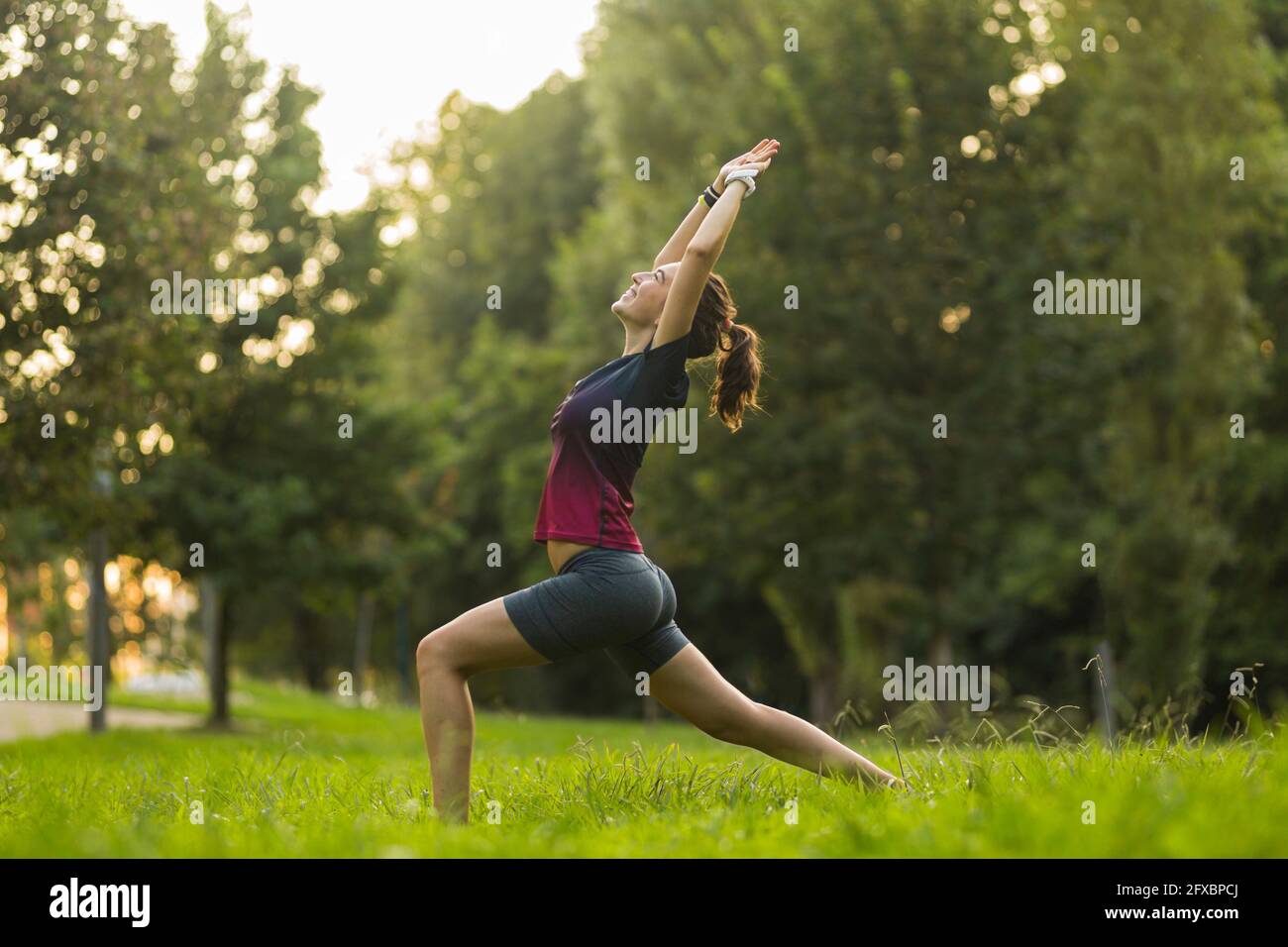 Junge Frau, die Krieger praktiziert, posiert Yoga im öffentlichen Park Stockfoto