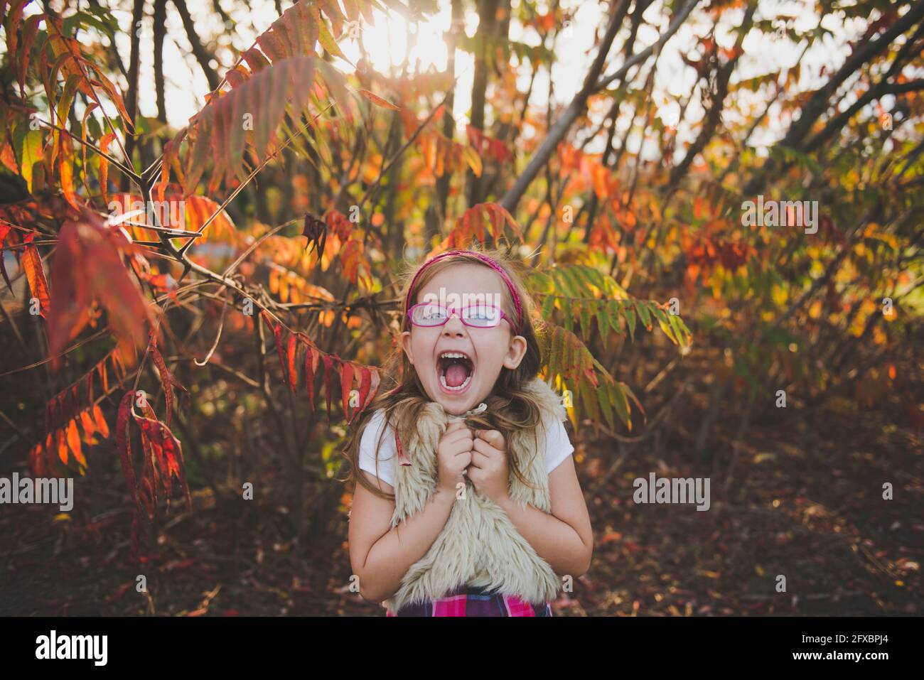 Fröhliches Mädchen mit offenem Mund vor den Pflanzen im Herbst Stockfoto