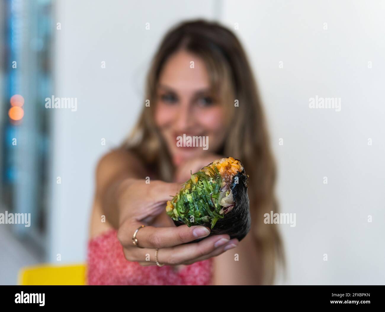Junge Frau hält Essen, während sie im Restaurant sitzt Stockfoto