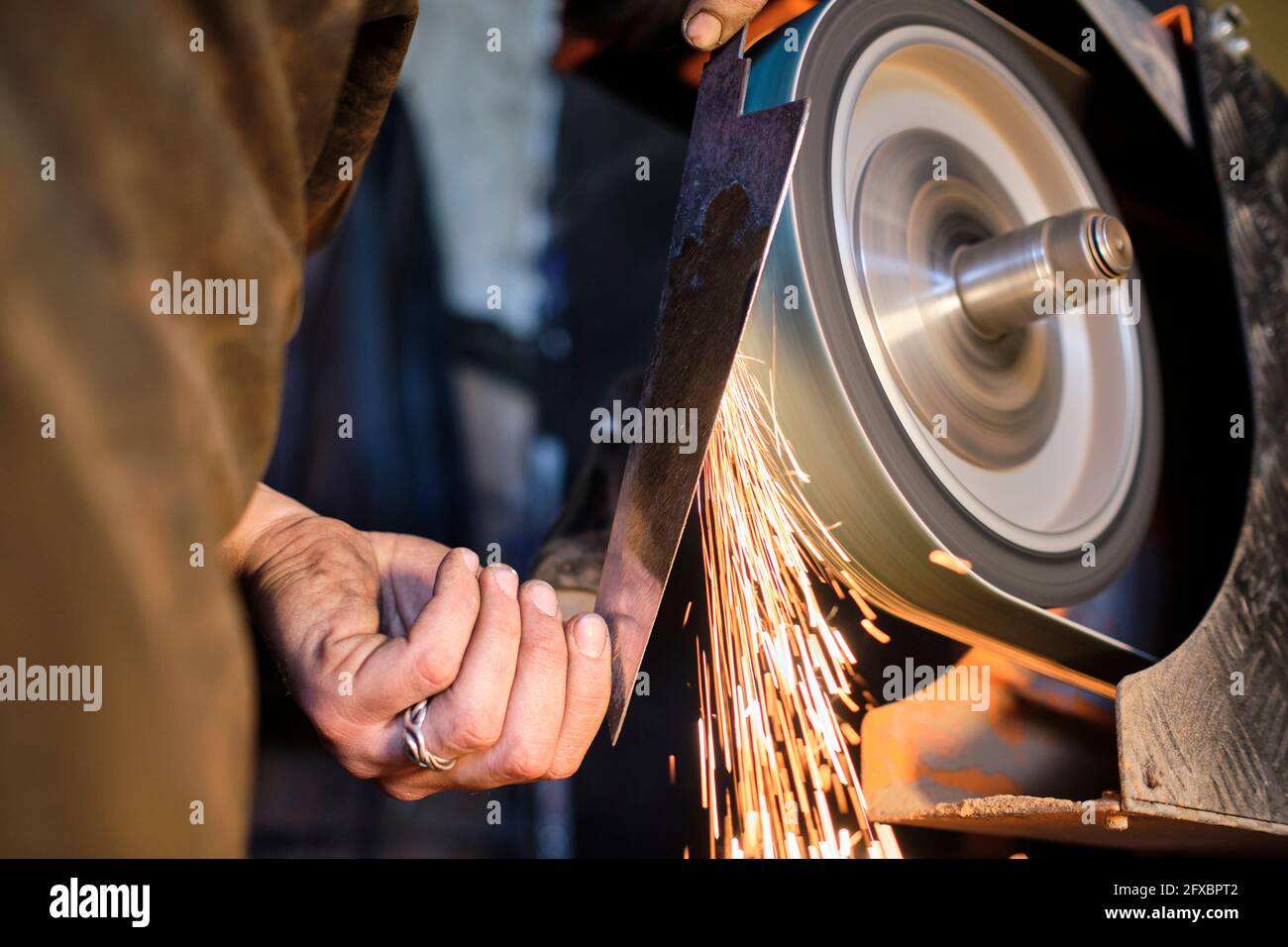 Männlicher Schmied schärft Messer Form Metall auf Schleifer in der Werkstatt Stockfoto