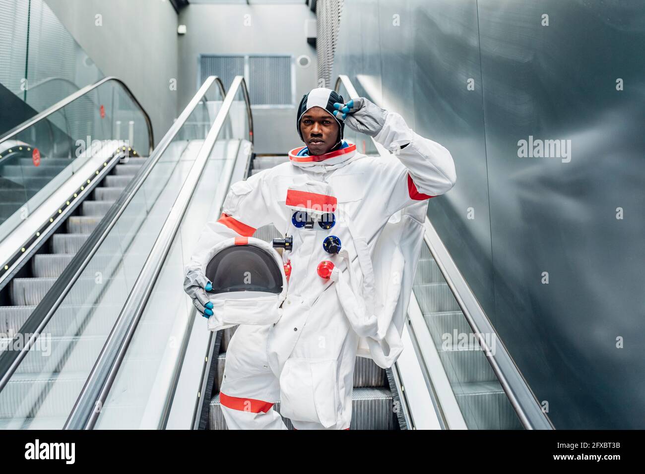 Selbstbewusster männlicher Astronaut grüßend auf der Rolltreppe Stockfoto