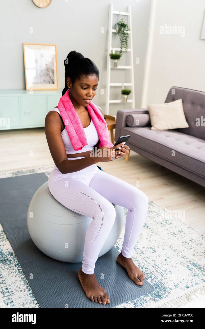 Aktive junge Frau, die zu Hause auf dem Fitnessball sitzt Stockfoto
