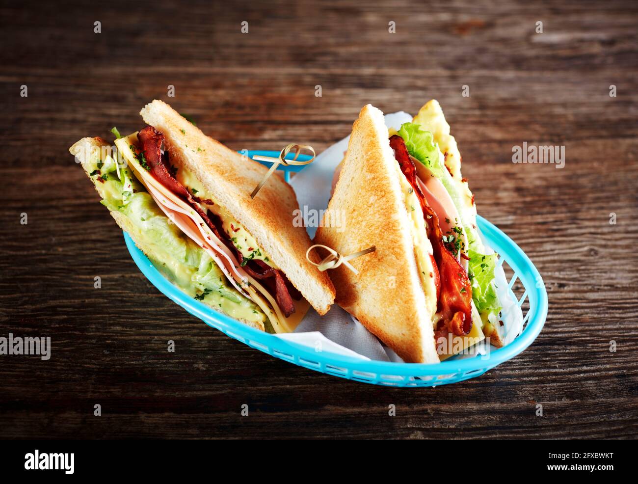 Studioaufnahme von zwei Sandwiches mit Schinken, Speck, Käse und Salat Stockfoto