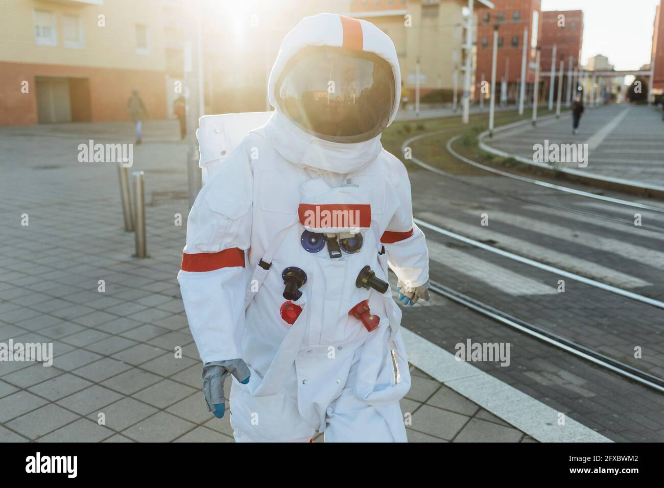 Frau Astronautin im Raumanzug zu Fuß in der Nähe von Straßenbahnlinien in der Stadt Stockfoto