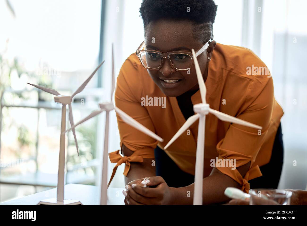 Frau mit Brille, die im Büro Modelle von Windenergieanlagen untersucht Stockfoto