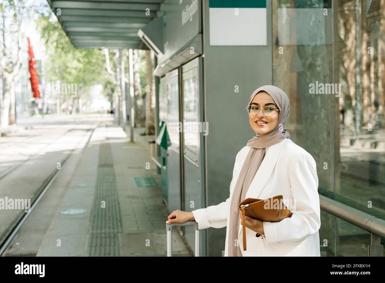 Schöne Frau hält Geldbörse, während sie am Bahnhof steht Stockfoto