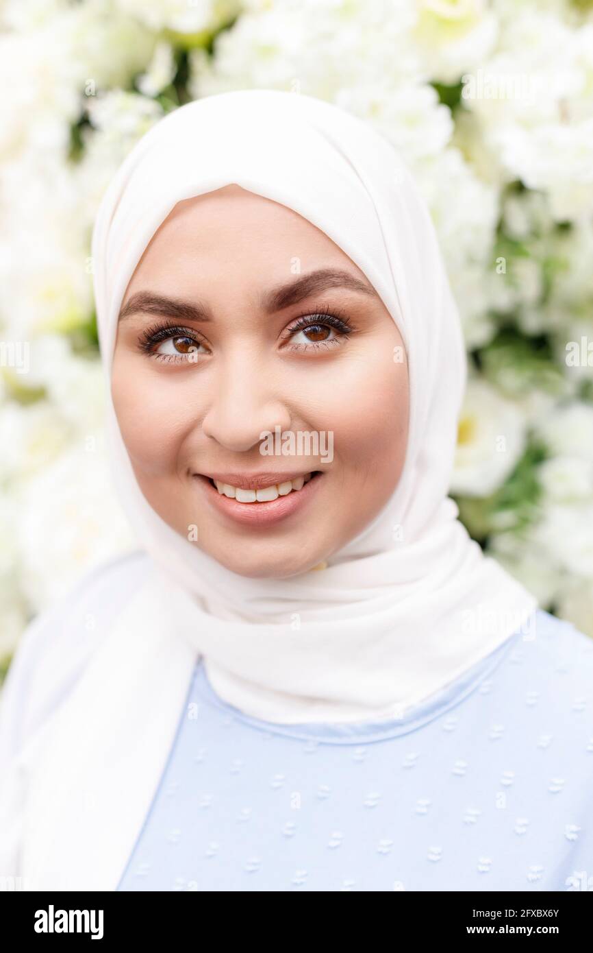 Glückliche Frau, die vor der weißen Blumendekoration wegschaut Stockfoto