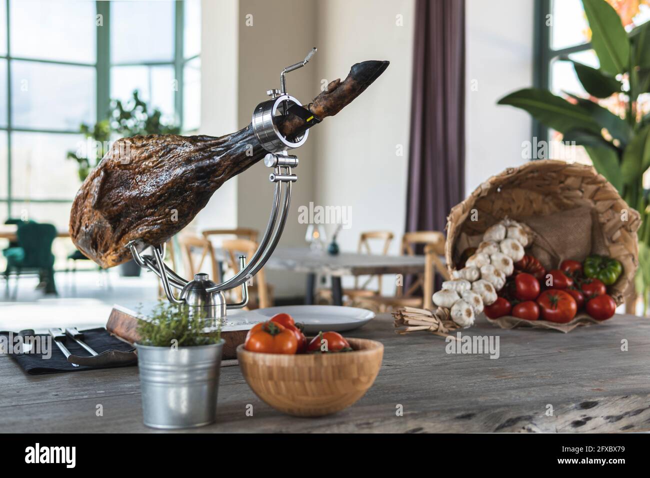 Schinken auf Schinkenhalter über dem Tisch im Restaurant Stockfoto