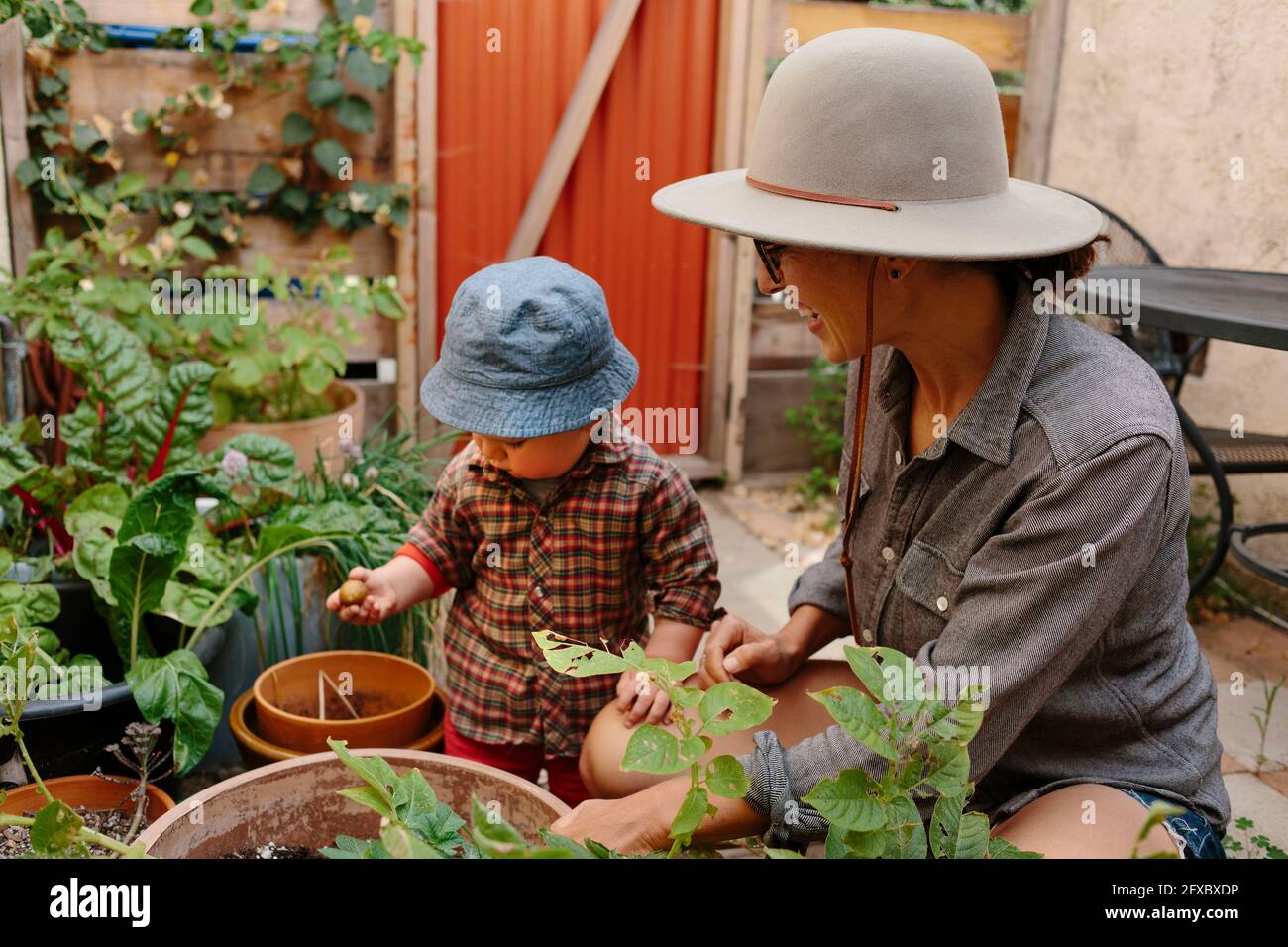 Mutter schaut auf Kleinkind Junge im Garten hinter dem Hof Stockfoto