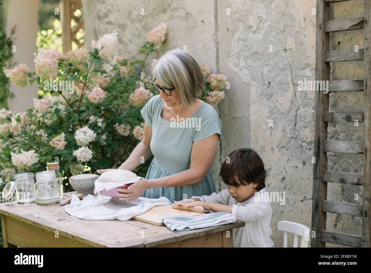 Netter Junge mit Großmutter, die im Hinterhof Brot backt Stockfoto