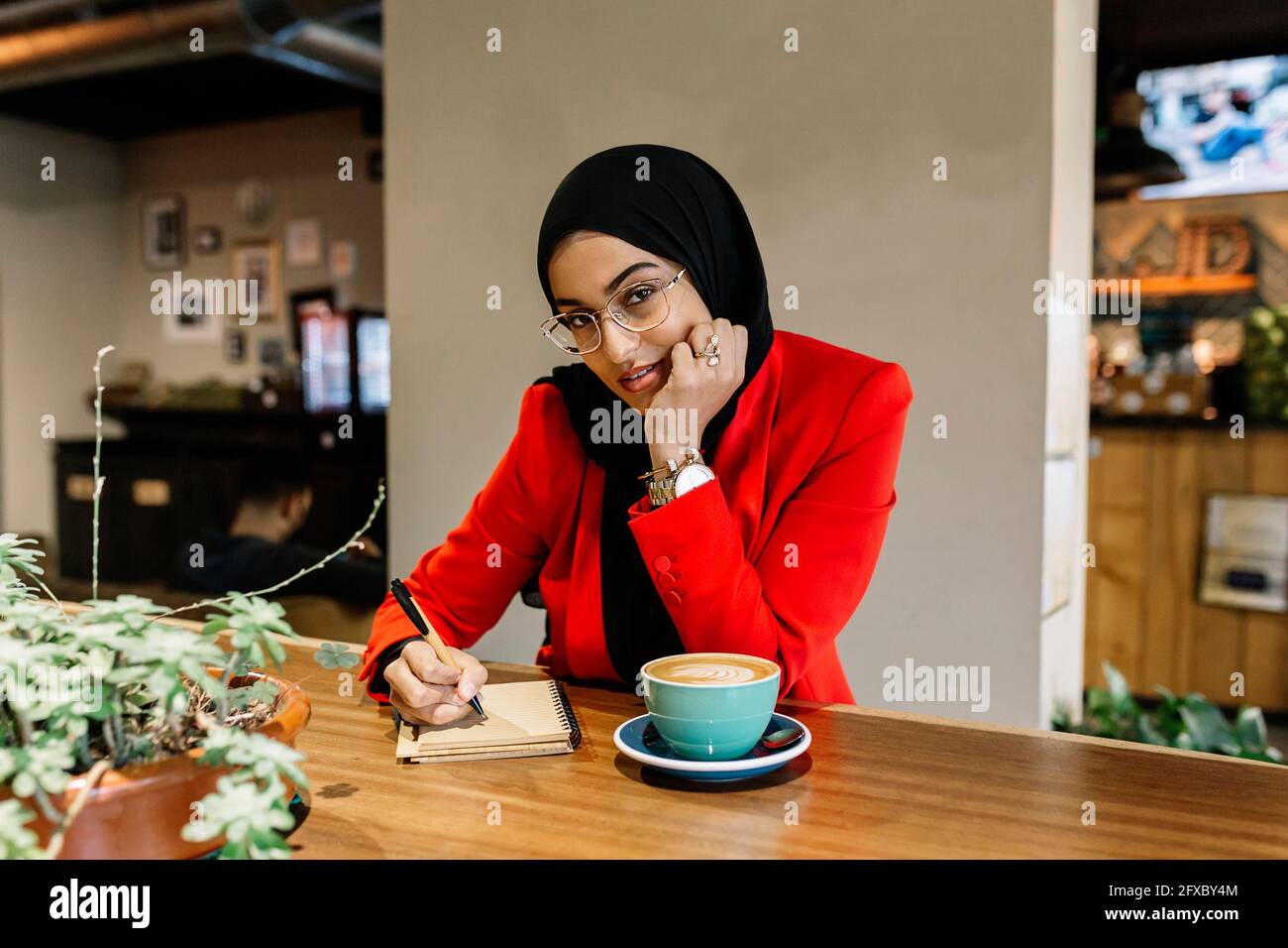 Junge Geschäftsfrau, die im Café Tagebuch schreibt Stockfoto