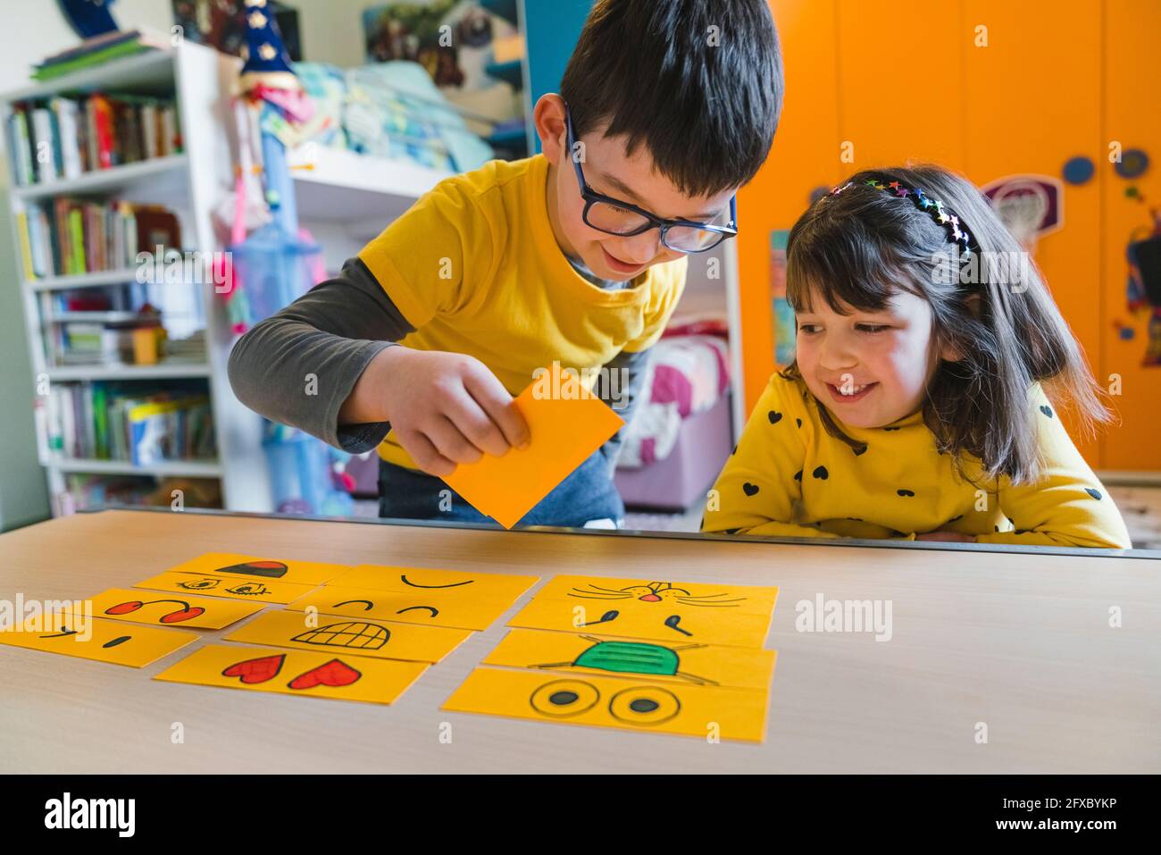 Verspielte Kinder mit Emoticons auf dem Tisch im Spielzimmer zu Hause Stockfoto
