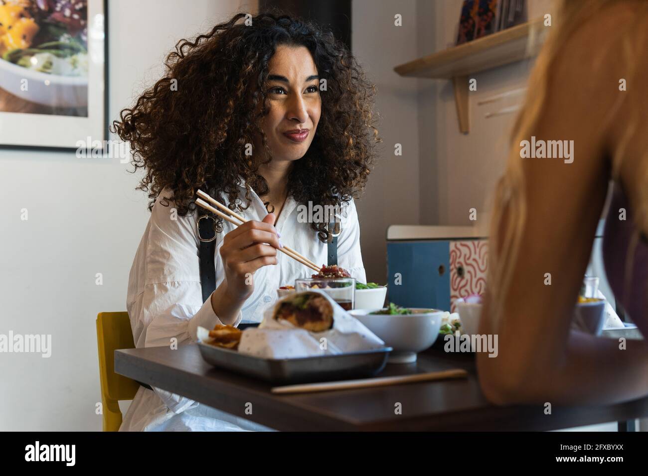 Junge Frau, die eine Freundin anschaut, während sie im Restaurant essen geht Stockfoto