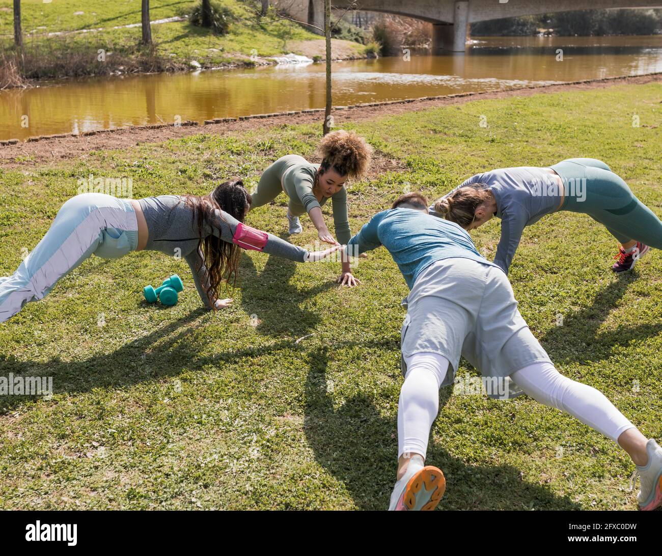 Männliche und weibliche Freunde trainieren an sonnigen Tagen im öffentlichen Park Stockfoto