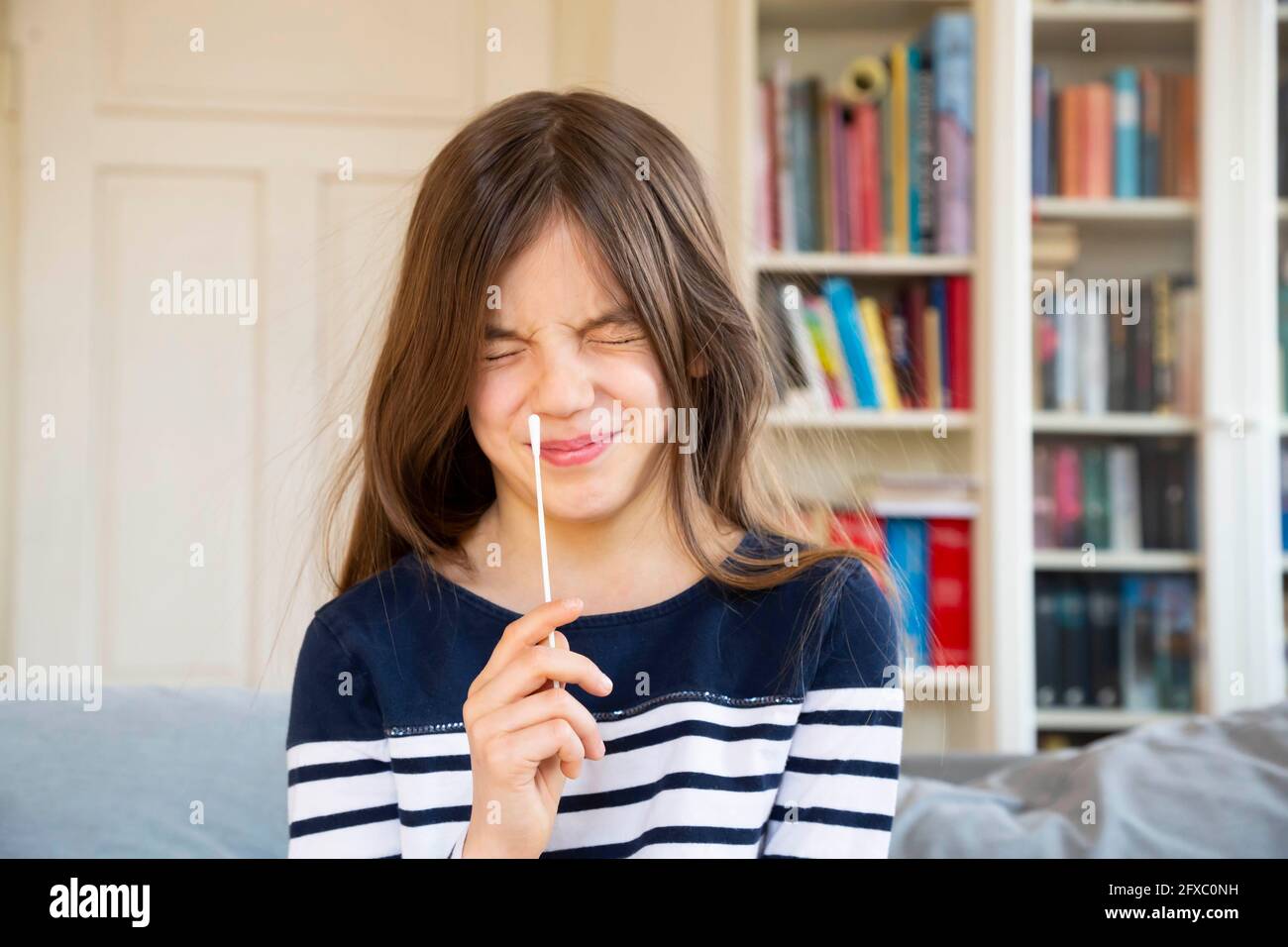 Mädchen schielt, während sie zu Hause einen Wattestäbchen in der Hand hält Stockfoto