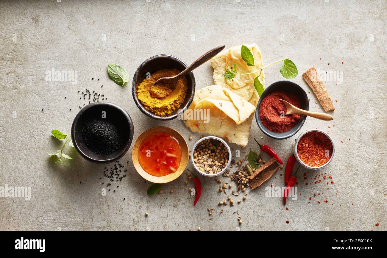 Studioaufnahme von Naan-Brot, Chili-Dipping-Sauce und Schüsseln mit verschiedenen Masala-Gewürzen Stockfoto