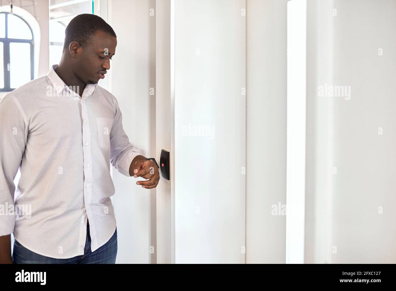 Geschäftsmann scannt Smart Watch, während er am Eingang des Büros steht Stockfoto