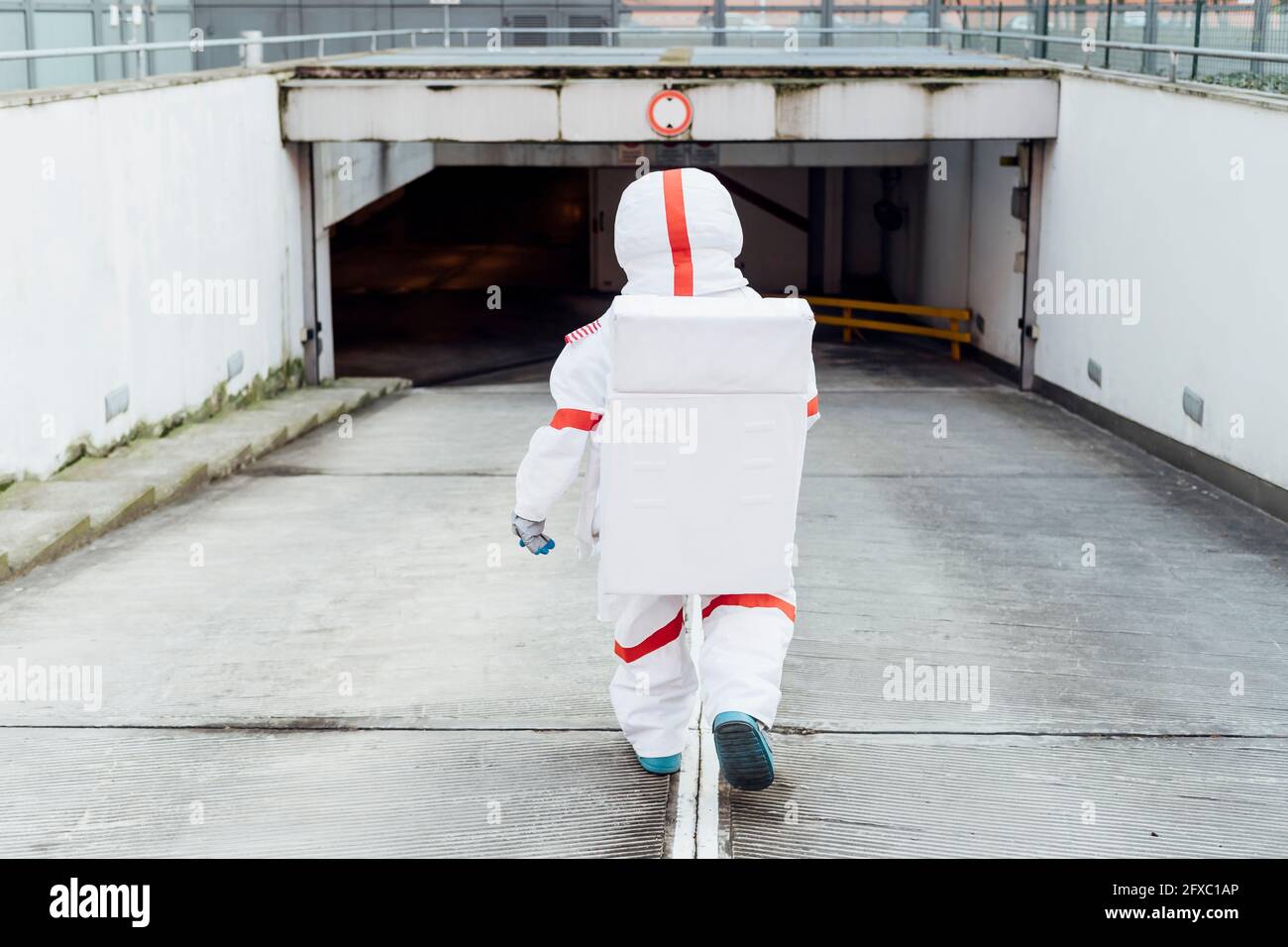 Die Astronautin trägt einen Raumanzug, während sie auf dem Parkplatz im Untergeschoss nach unten geht Stockfoto
