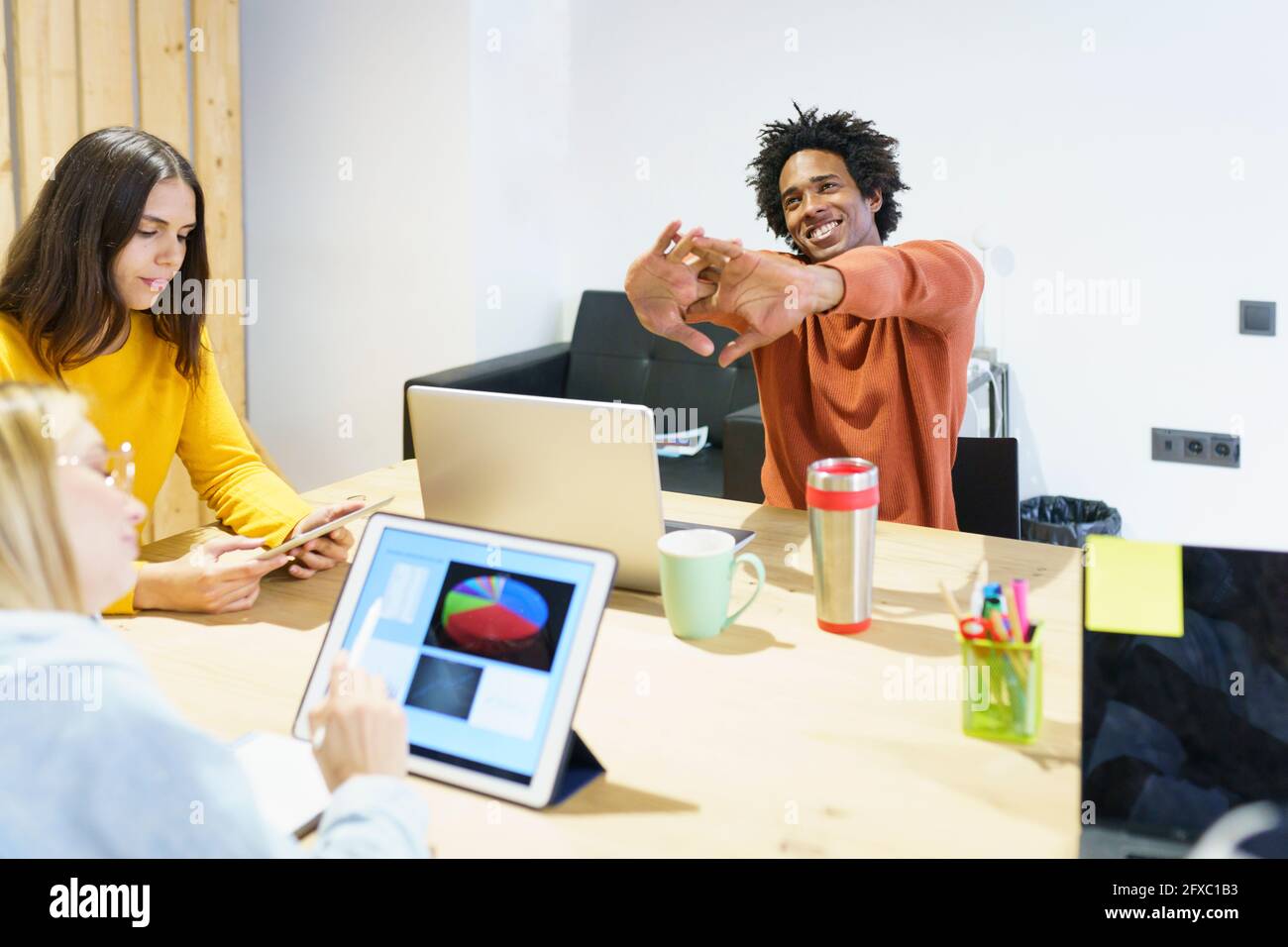 Männlicher Profi, der sich am Schreibtisch die Hände streckt Stockfoto Männlicher Profi, der sich am Schreibtisch die Hände streckt Stockfoto