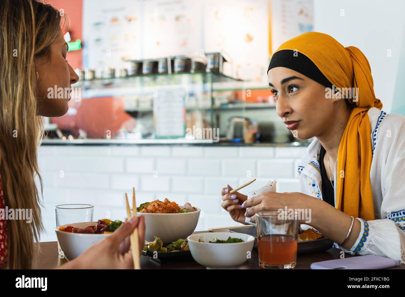 Junge Frauen, die sich beim Essen im Restaurant unterhalten Stockfoto