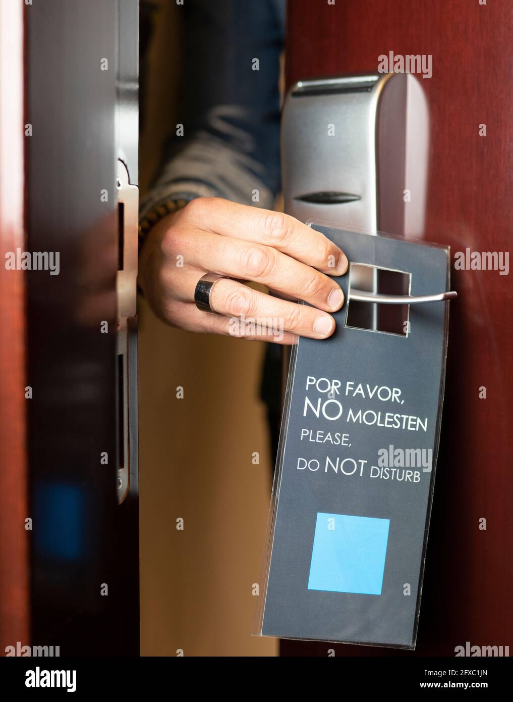 Mann, der das Schild „Bitte nicht stören“ an der Hoteltür hält Stockfoto