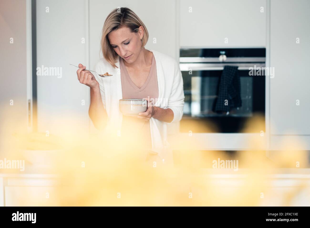 Blonde Frau zu Hause essen Stockfoto
