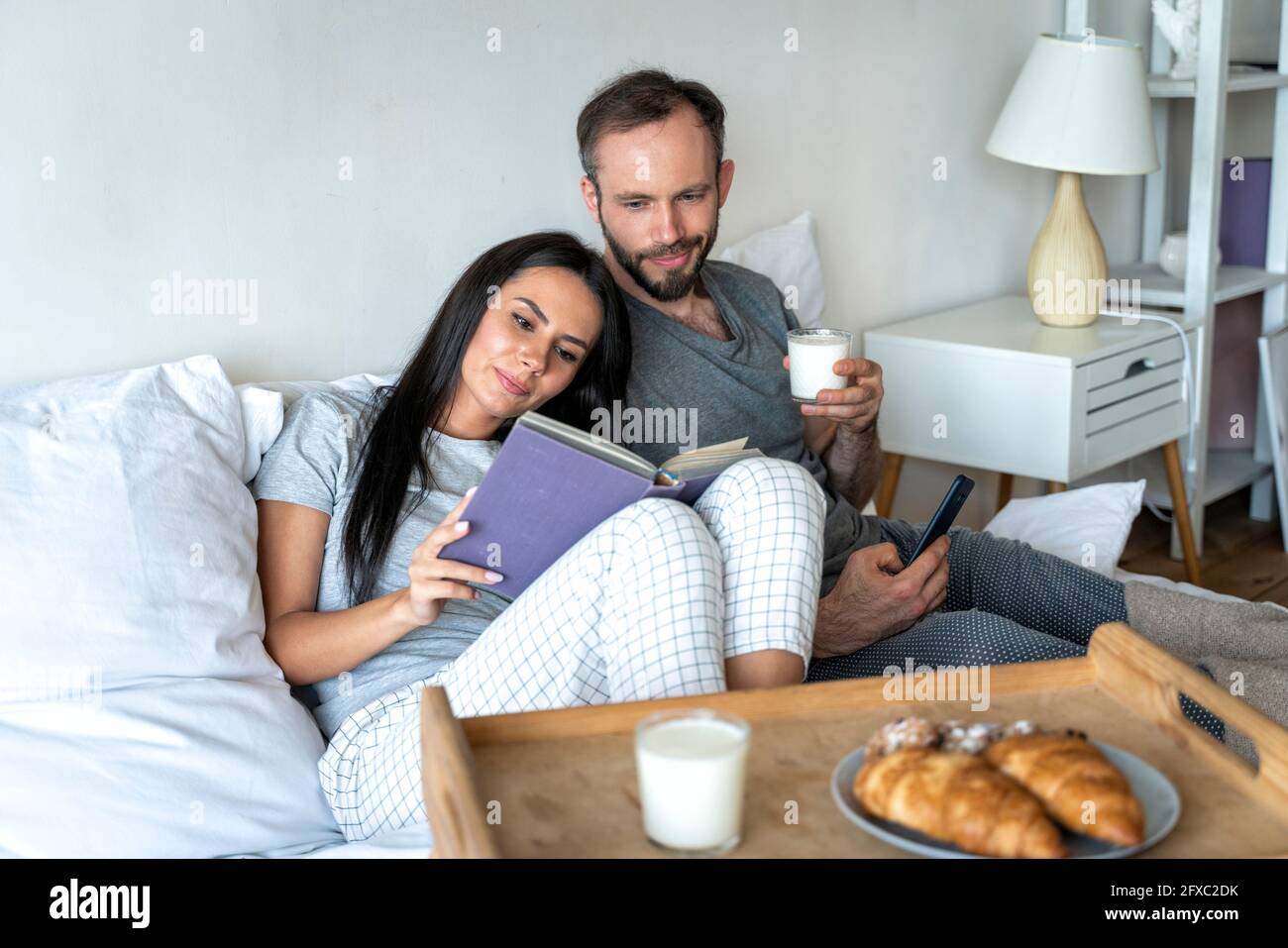 Mann und Frau frühstücken zu Hause auf dem Bett Stockfoto