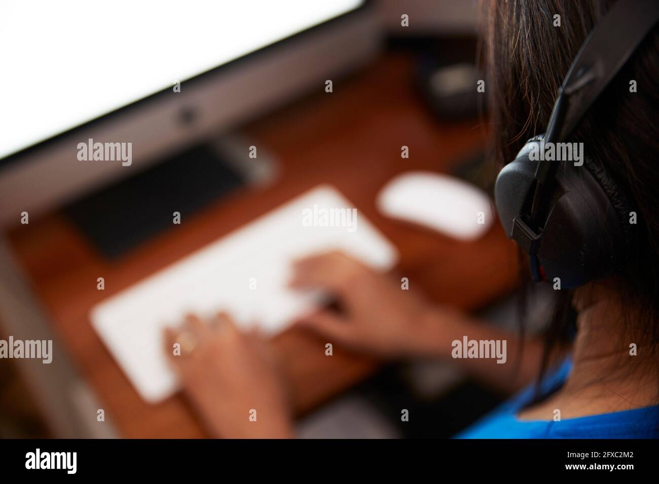 Frau mit Kopfhörern, die zu Hause am Computer arbeitet Stockfoto