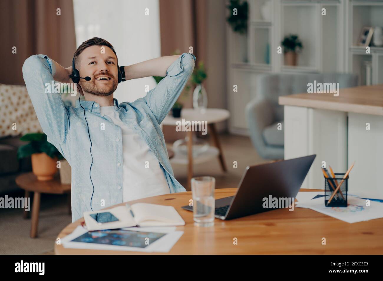 Glücklicher Kerl mit Headset und Mikrofon, der Online-Video-Chat genießt Stockfoto