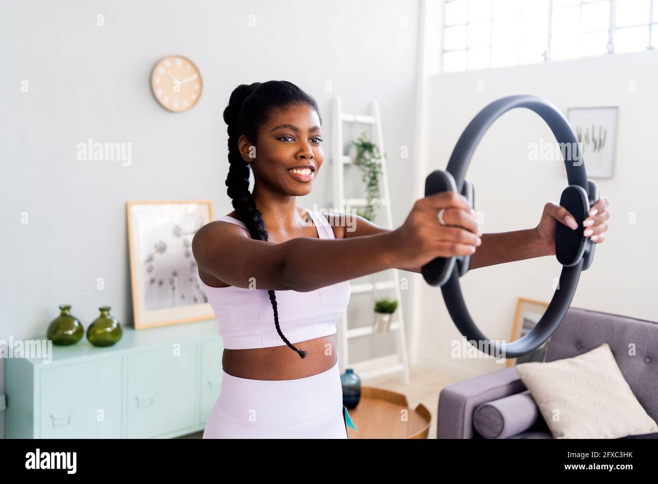 Lächelnde Frau, die zu Hause mit Pilates-Ring trainiert Stockfoto