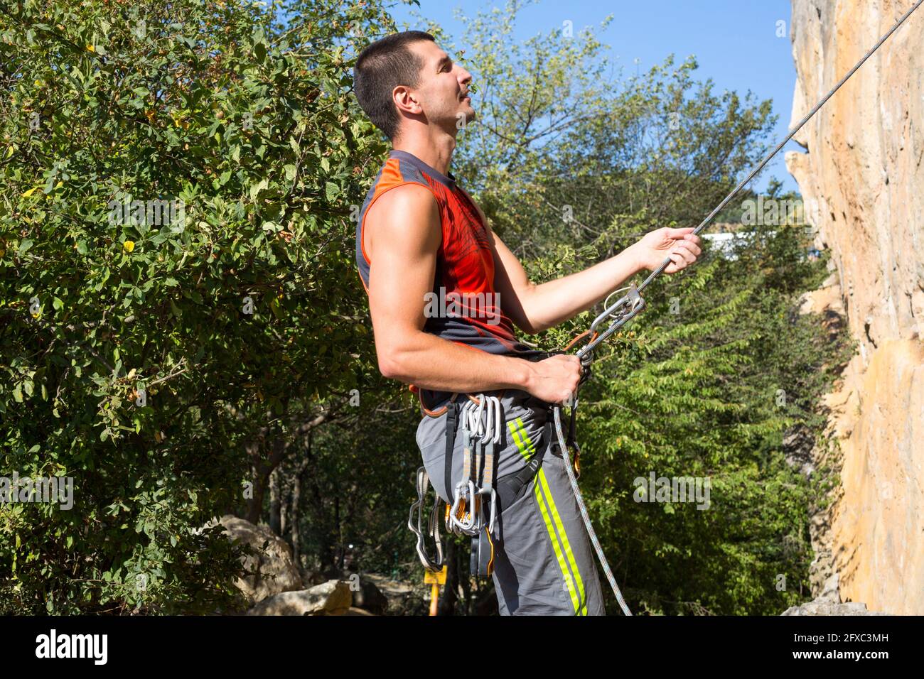 Kletterausrüstung an einem männlichen Kletterer: Felsschuhe, Seil, Schnellzug, Sicherheitsvorrichtung, Geschirr. Sport Bergtourismus, aktiver Lebensstil, Extremsport Stockfoto