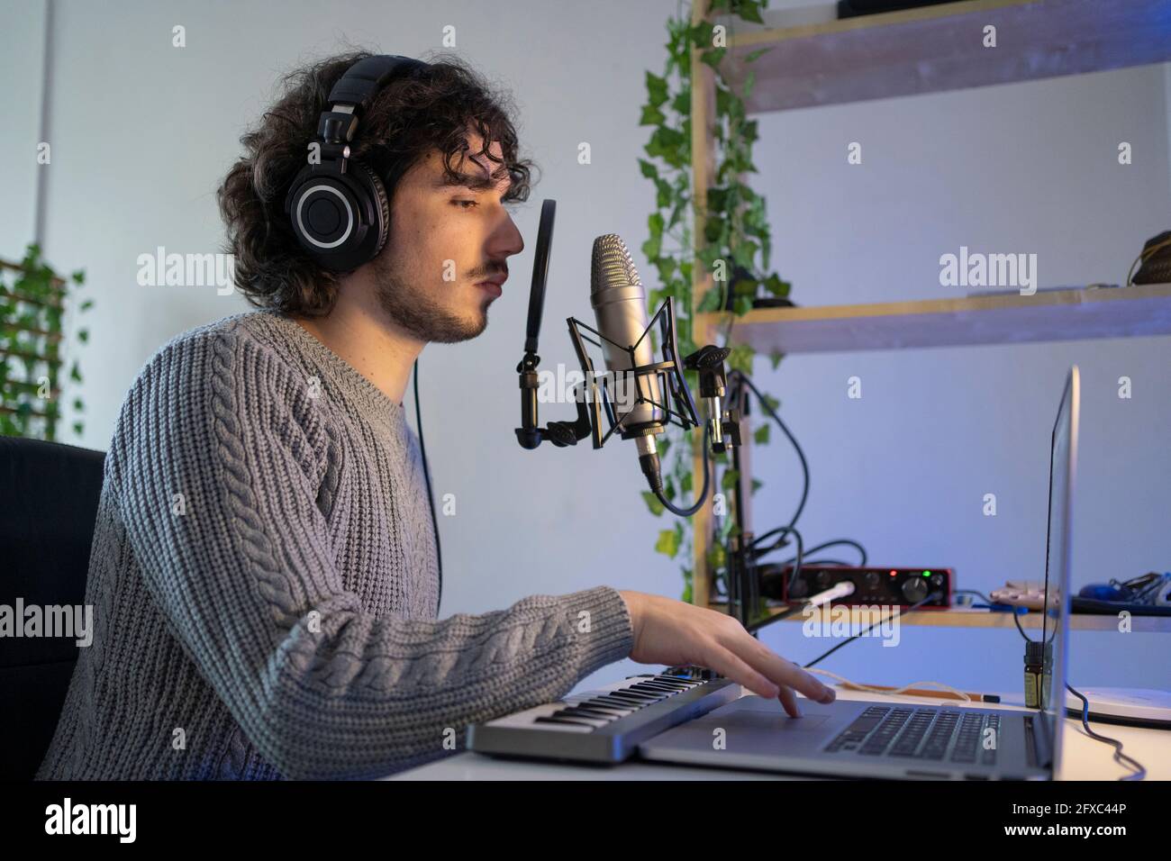Männlicher Musikkomponist mit Tonaufnahmesequipment und Laptop zu Hause Stockfoto