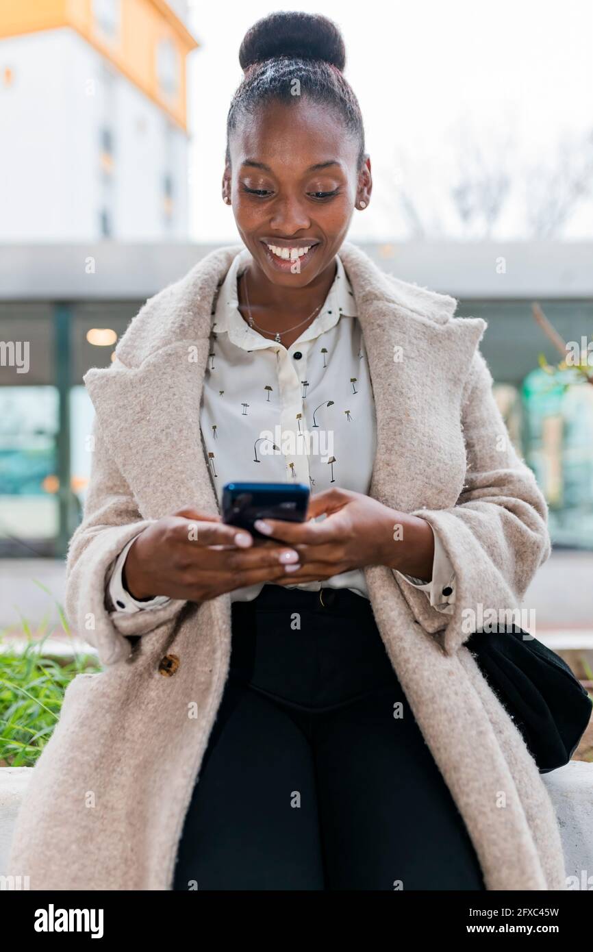 Lächelnde afrikanische Frau, die im Freien mit einem Mobiltelefon telefoniert Stockfoto