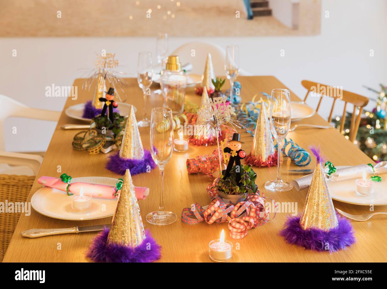 Festlich gedeckten Silvestertisch mit Tellern, Kerzen, Partyhüten, Sektflöten und Kaminfeger-Figuren Stockfoto