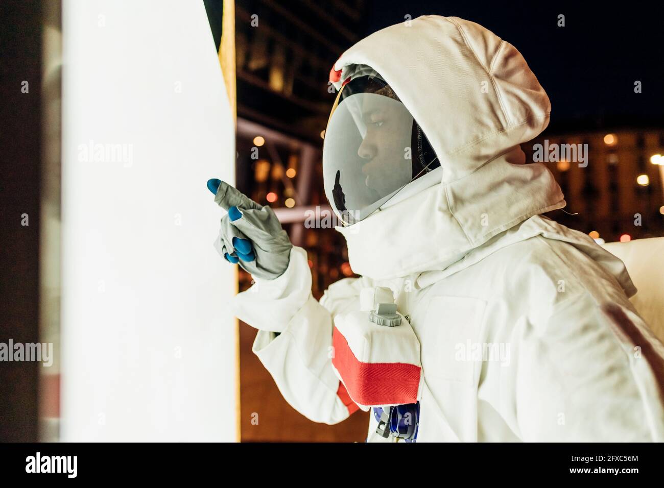 Männlicher Astronaut zeigt auf beleuchtete Wand Stockfoto