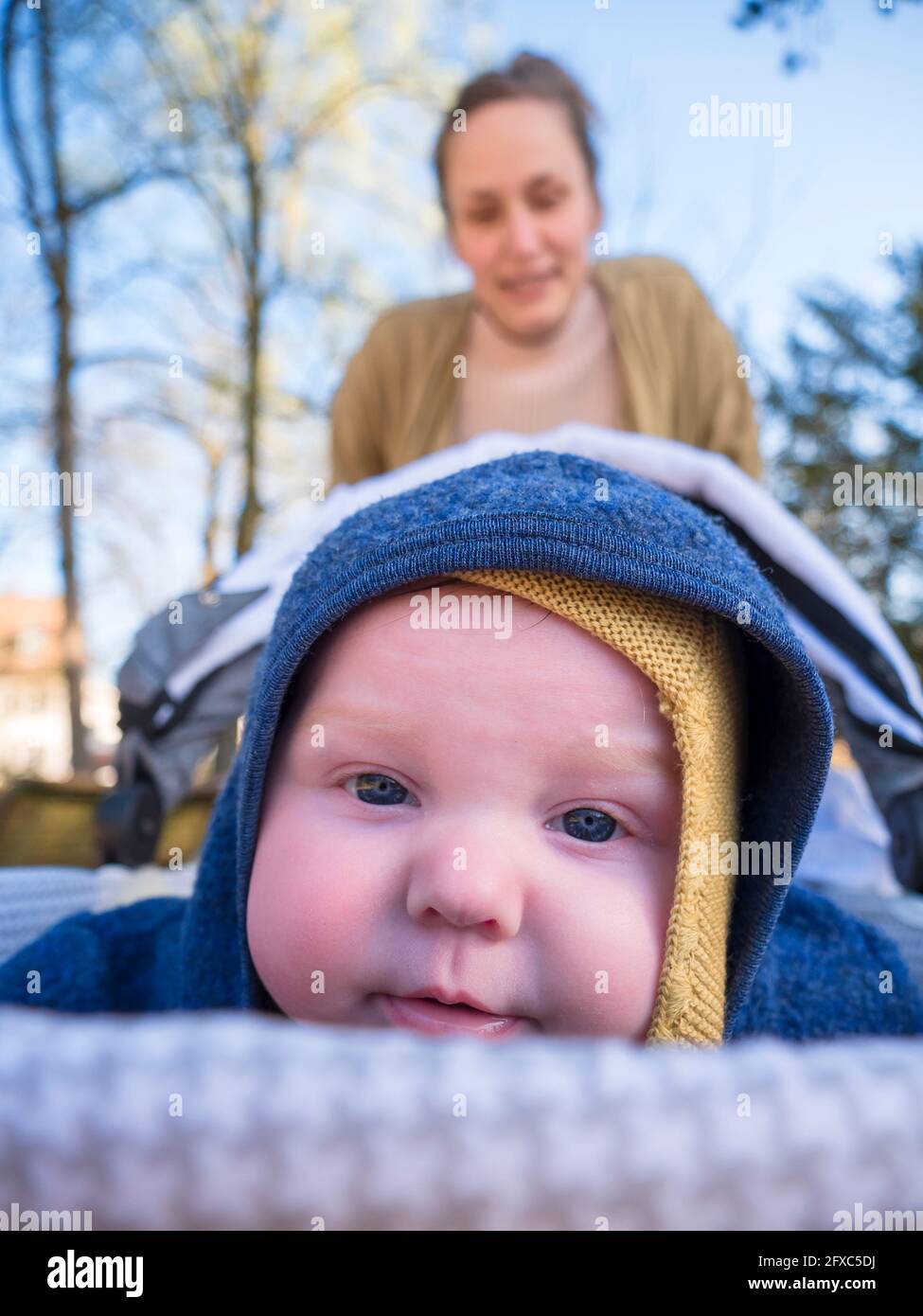 Nettes Baby Mädchen mit Mutter im Hintergrund auf Spielplatz Stockfoto